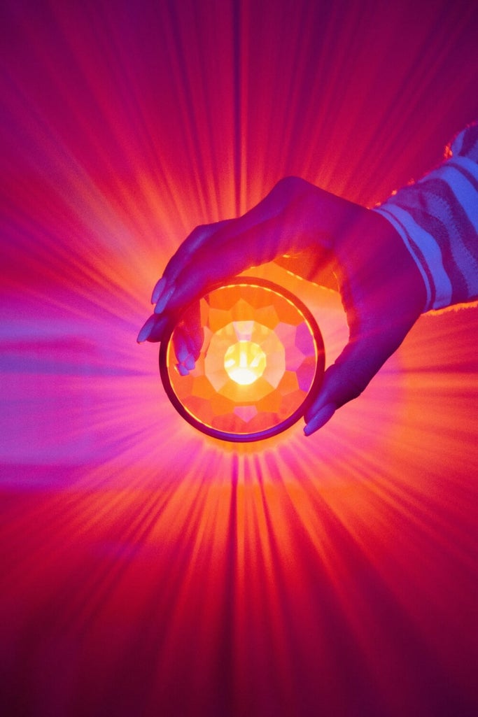 Girl holds prism lens in front of bright red light to elevate projector photoshoot.
